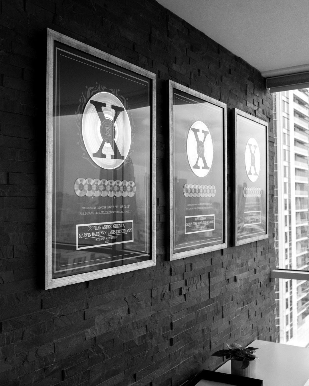 Drei gerahmte 8-Figure Awards an einer dunklen Steinwand