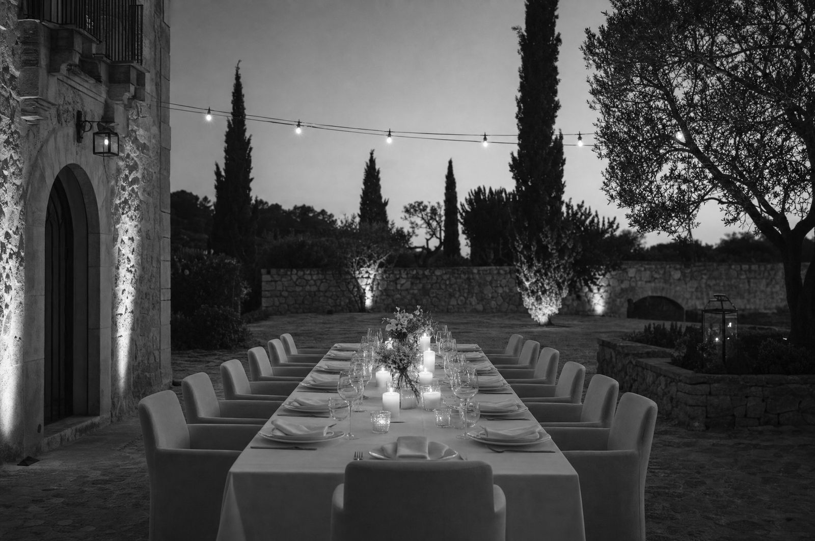 Eine lange, festlich gedeckte Tafel im Garten am Abend